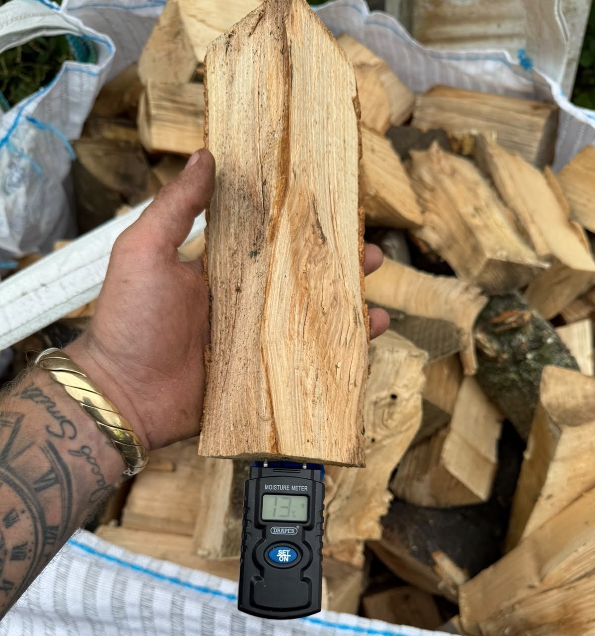 Moisture meter showing 13% moisture content in seasoned hardwood logs